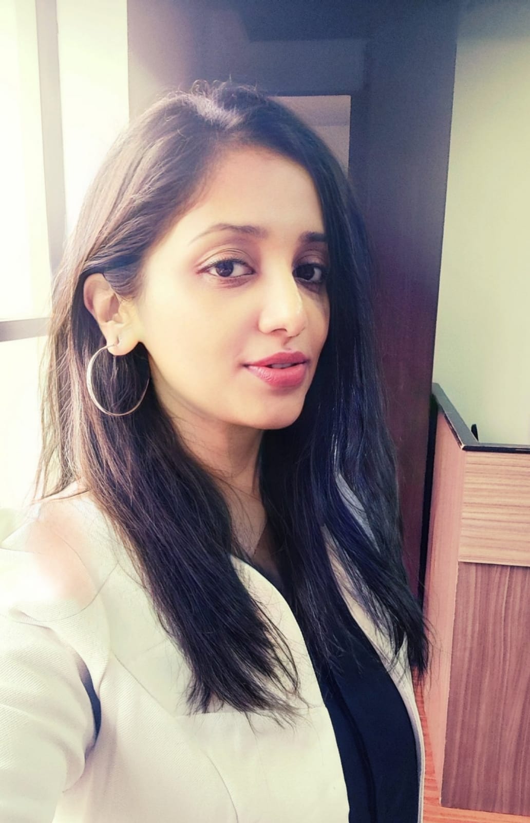 Portrait of a woman with long hair wearing a white blazer, smiling